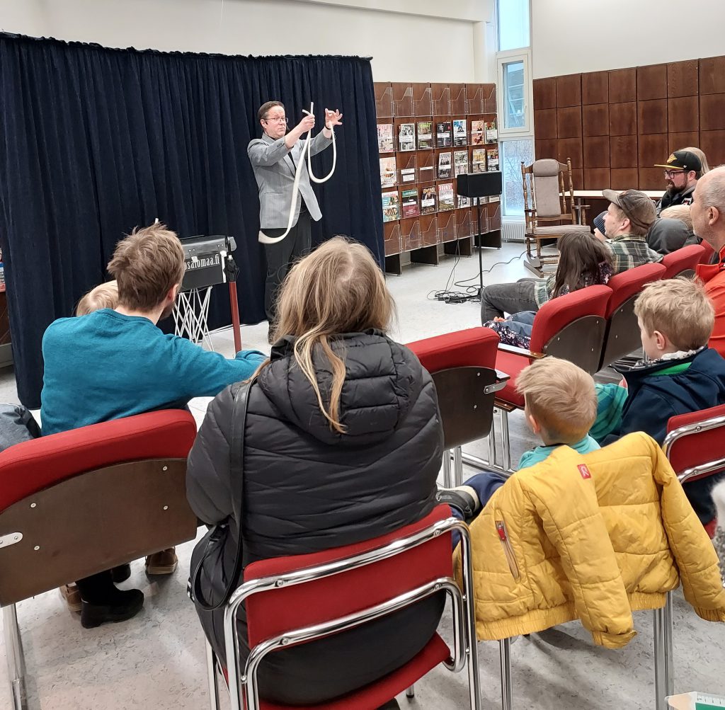 Taikuri tekee temppua naruilla lapsiyleisön edessä.